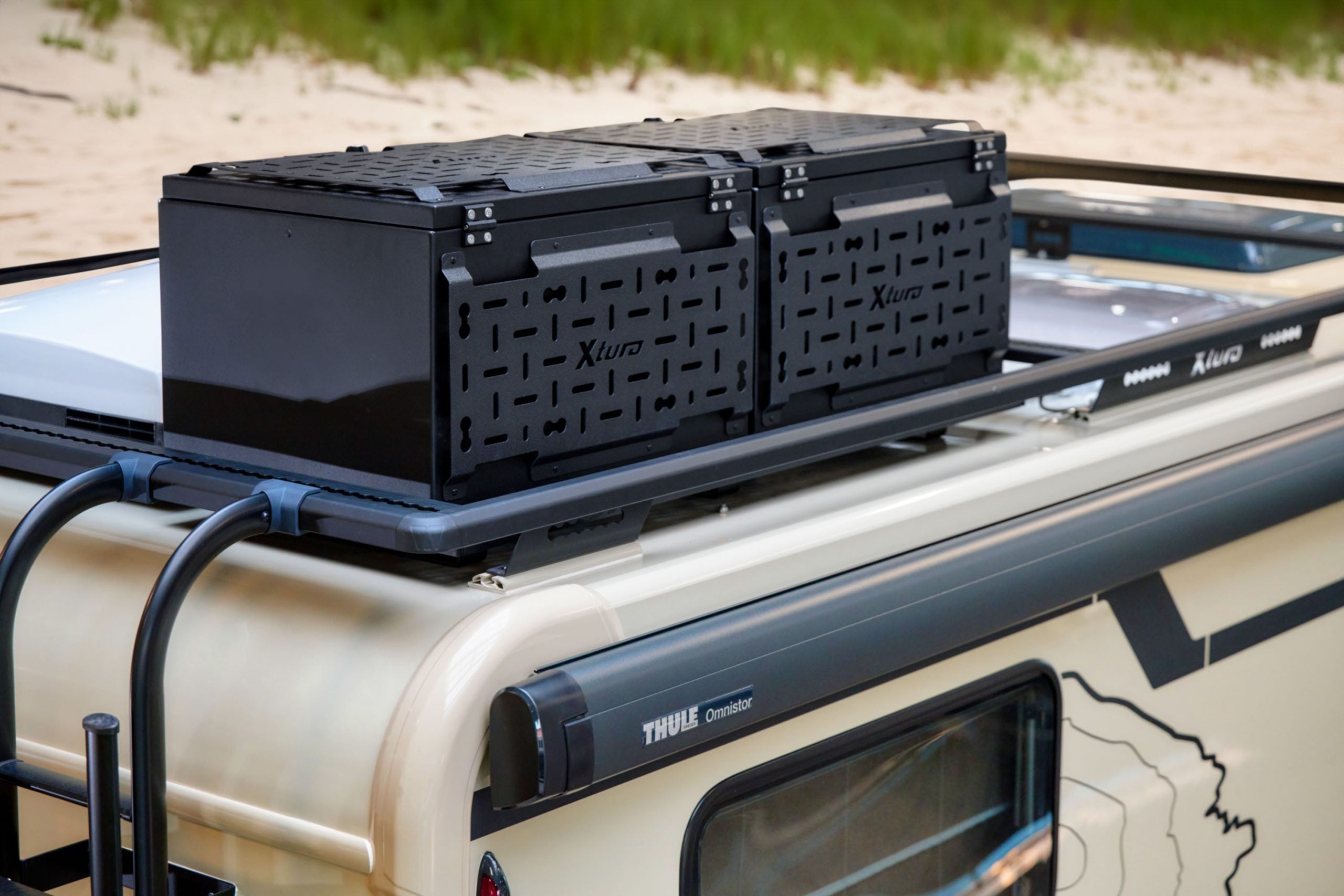 Deux caissons noirs constituent le chargement sur le toit d'un camping-car.