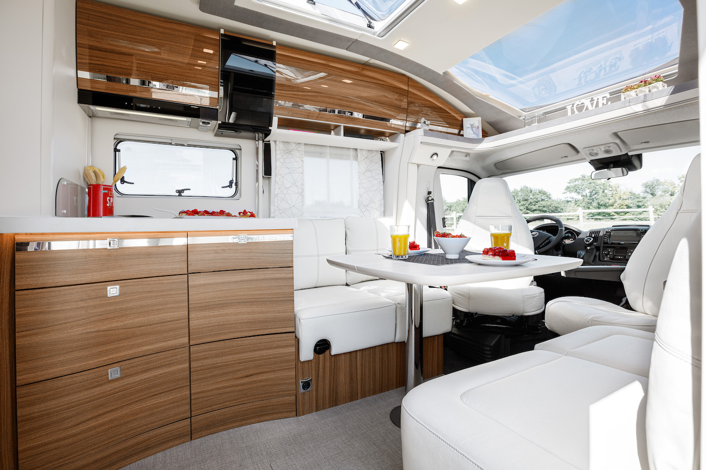 Vue intérieure d'un camping-car avec table, armoires et rangée de sièges.