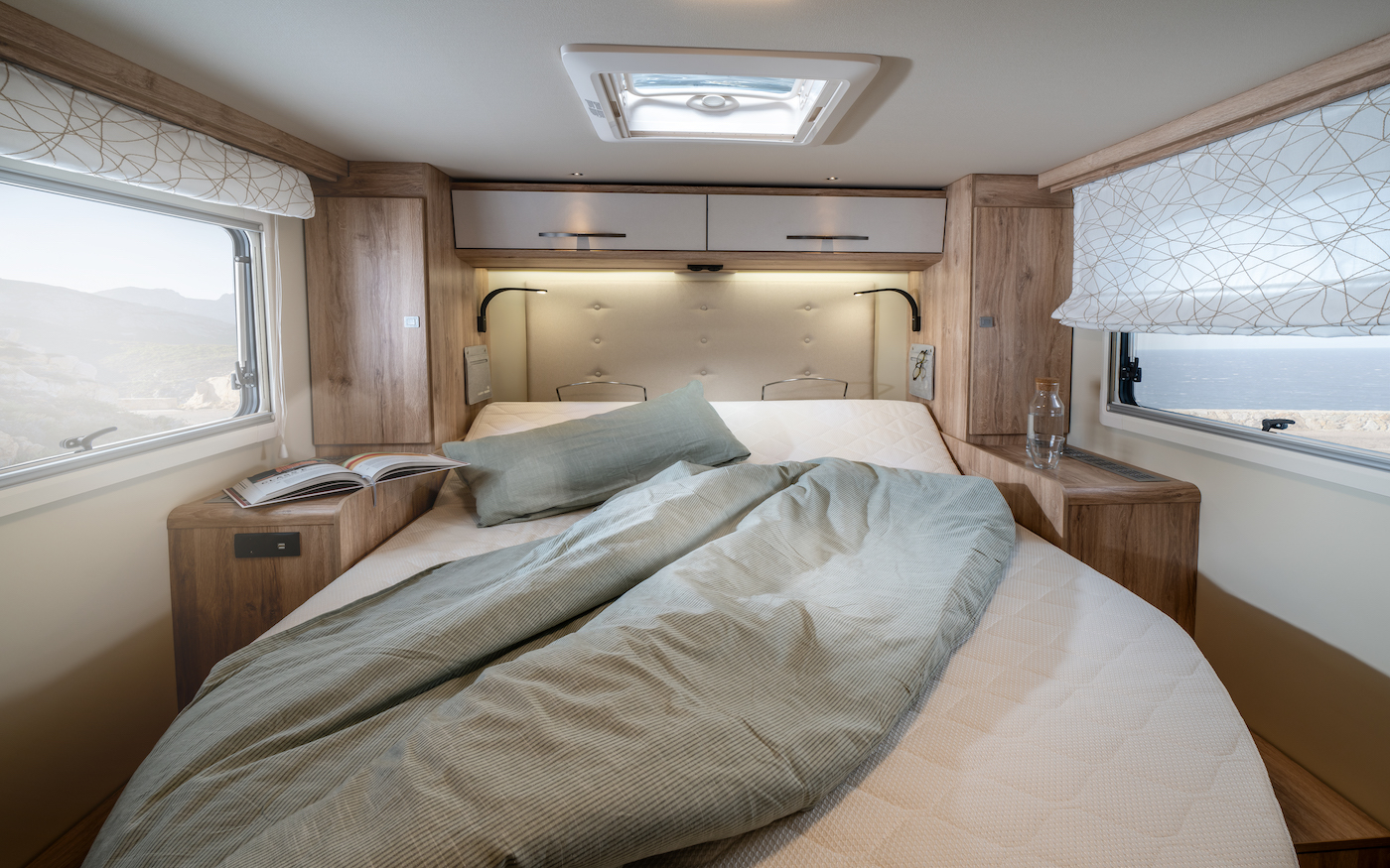 Lit double avec plafond gris et éclairage à la tête de lit.