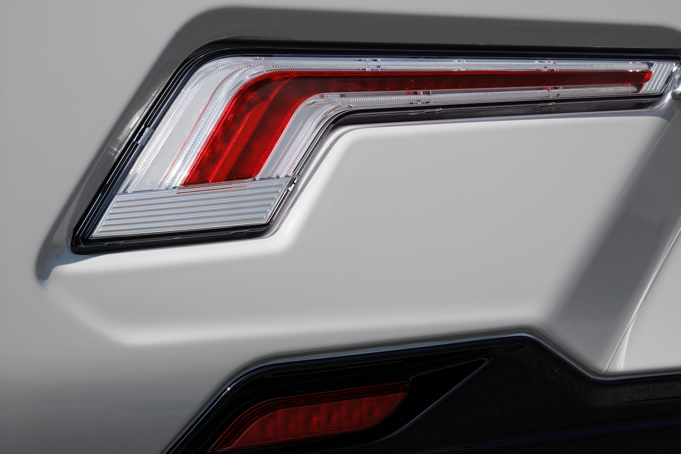 Gros plan sur un feu extérieur rouge, à côté d'une carrosserie blanche.