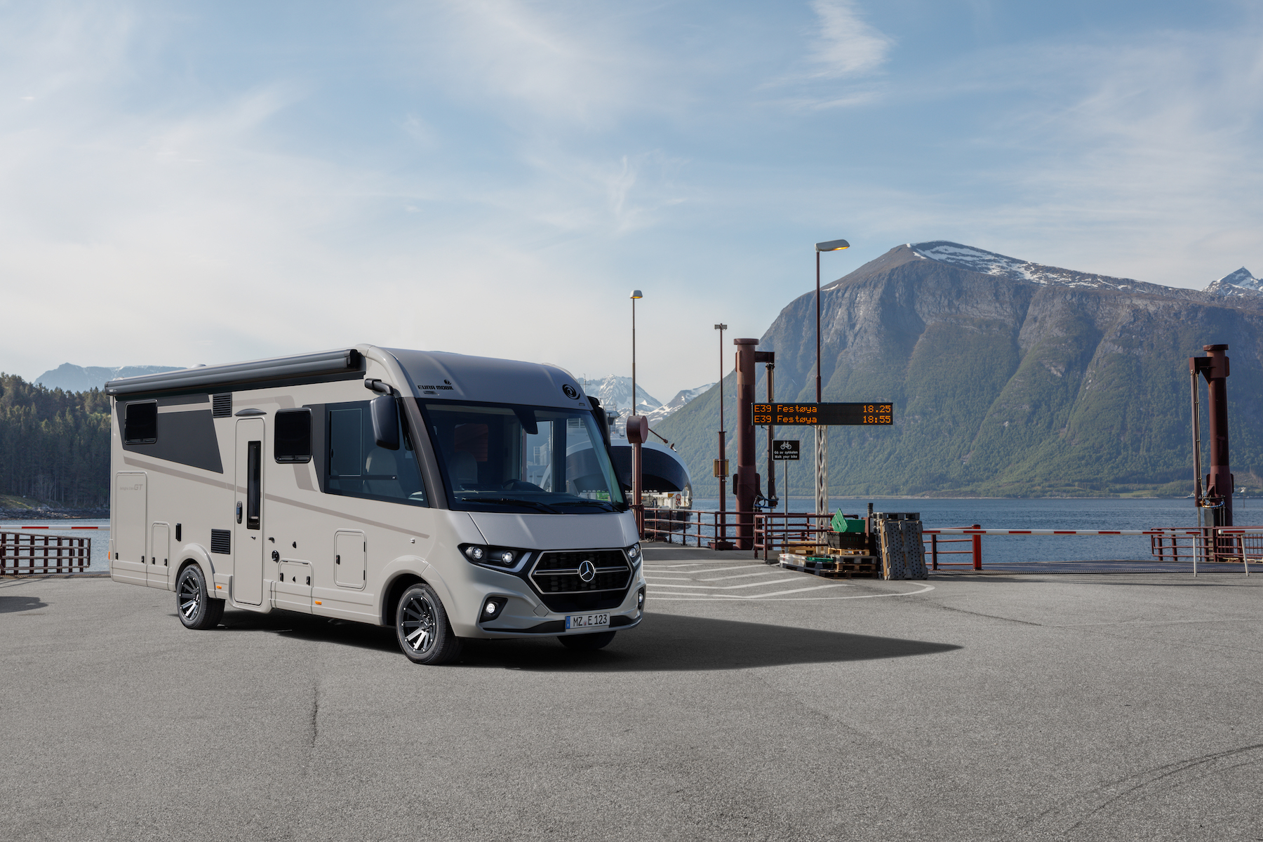 Vue latérale d'un camping-car avec le contour d'une montagne en arrière-plan.