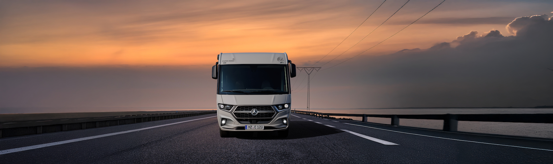 Vue panoramique d'un camping-car sur fond de ciel rougeâtre.
