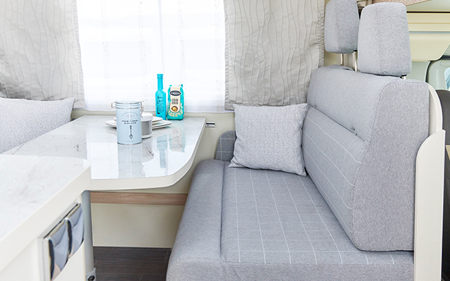 A droite, il y a un simple coin salon gris, devant lequel se trouve une table.